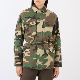 Model wearing green and brown camouflage print cotton utility jacket with chest pockets and elasticated waist, styled with khaki trousers