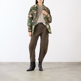 Model wearing camouflage print military jacket, styled with khaki tapered trousers and black ankle boots