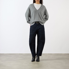 Model wearing Nili Lotan Pebble Grey Heather V-neck knit sweater, styled with dark navy trousers and black ankle boots.