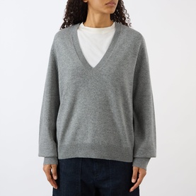 Model wearing Nili Lotan pebble grey heather V-neck knit sweater, styled with a white top and dark denim jeans.