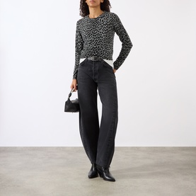 Model wearing Nili Lotan pebble grey heather and black cheetah print knit top with dark wash jeans, carrying a small black bag.