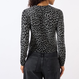 Model wearing Nili Lotan knitwear in Pebble Grey Heather/Black Cheetah print, long sleeves, back view, styled with dark grey jeans.