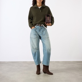 Model wearing Nili Lotan Renata Turtleneck Sweater in Dark Pine Melange, styled with light-wash barrel-leg jeans and brown ankle boots.