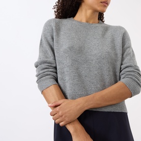 Model wearing Nili Lotan pebble grey heather knit sweater with ribbed cuffs and hem, styled with navy trousers