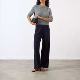 Model wearing Nili Lotan Pebble Grey Heather knit top, styled with wide-leg navy trousers, tan sandals, and a small black bag.