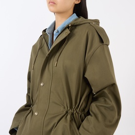 Model wearing Nili Lotan Lucienne Parka Jacket in Army Green, showing hood, snap button placket and drawstring waist, styled with a denim shirt.