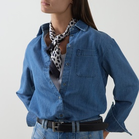 Model with Nili Lotan Savanna Silk Twill Scarf in Cheetah Print, tied at neck, styled with blue denim shirt and black belt