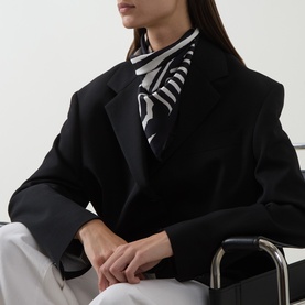 Model with Nili Lotan Zebra Silk Twill Scarf in zebra print, styled as necktie with black blazer and white trousers