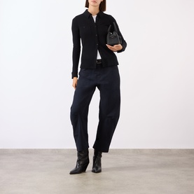 Model wearing Nili Lotan black wool shirt with navy trousers and black ankle boots, carrying a small black bag.