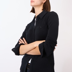 Model wearing Nili Lotan black 100% wool shirt, arms crossed, showing collar and button-front detail.