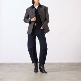 Model wearing Nili Lotan black wool shirt layered under a grey check blazer with dark indigo jeans and black ankle boots