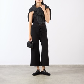 Model wearing Nili Lotan Kiki Drawstring Flared Sweatpants in Washed Black with raw hems, styled with black top, scarf and mini bag.