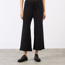 Model wearing Nili Lotan Kiki Drawstring Flared Sweatpants in Washed Black, mid-rise with flared-cut leg and raw hems, styled with black trainers.