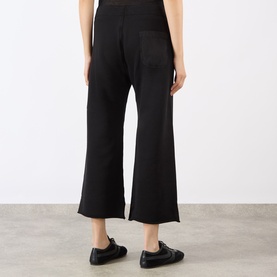 Model wearing Nili Lotan Kiki Drawstring Flared Sweatpants in Washed Black, showing rear patch pocket and raw-hem flared crop leg.
