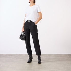 Model wearing Nili Lotan white cotton T-shirt, styled with black tapered trousers, belt, ankle boots, and small black handbag.