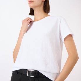 Model wearing Nili Lotan white cotton T-shirt with crew neck and short sleeves, styled with black trousers and white belt.