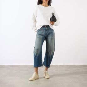Model wearing Nili Lotan Gladys Sweatshirt in Ecru with crew neck, styled with mid-blue barrel-leg jeans and white trainers, carrying black mini bag.