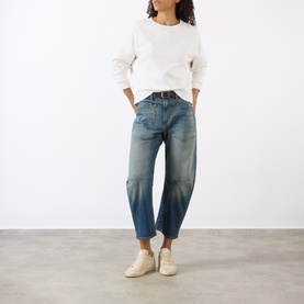 Model wearing Nili Lotan Gladys Sweatshirt in Ecru with crew neck and dropped shoulders, styled with mid-blue barrel-leg jeans and white trainers.