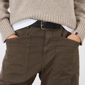Model wearing Nili Lotan trousers in Vintage Washed Dark Walnut cotton, styled with a cream knit, white shirt and black leather belt.
