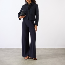 Model wearing Nili Lotan midnight wide-leg trousers, styled with matching navy jacket, brown sandals and black clutch bag.