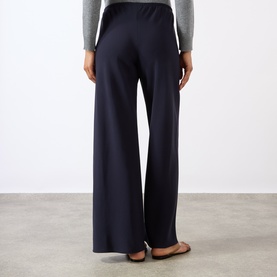 Model wearing Nili Lotan midnight wide-leg trousers, back view, styled with a grey knit top and flat ballet shoes.