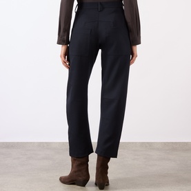 Model wearing Nili Lotan midnight wool trousers, rear view, styled with a brown sheer blouse and brown ankle boots