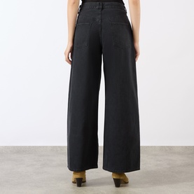 Model wearing black wide-leg trousers, rear view, styled with tan heeled mules