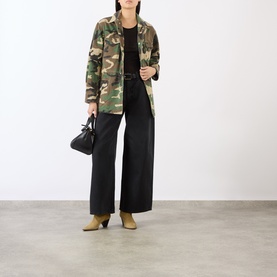 Model wearing camouflage print military jacket with black wide-leg trousers and tan ankle boots, carrying a small black bag