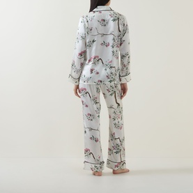 Model wearing Olivia von Halle Lila Ana Blossom Pyjama Set in white floral silk, rear view, long-sleeve shirt and full-length trousers