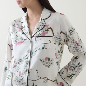 Model wearing Olivia von Halle Lila Ana Blossom Pyjama Set in white silk with pink cherry blossom print and contrast black piping