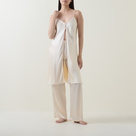 Model wearing Olivia von Halle Elvira Camisole Pyjama Set in bone silk, featuring a longline cami top with lace-up detail and wide-leg trousers.