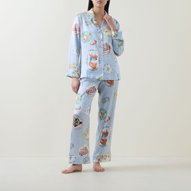 Model wearing Olivia von Halle Lila Cadiz Seafood Pyjamas in blue silk with all-over seafood print, long sleeves and full-length trousers
