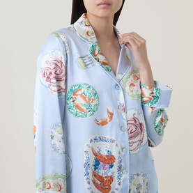 Model wearing Olivia von Halle Lila Cadiz Seafood Pyjamas in light blue silk with multicolour seafood medallion print, button-front top