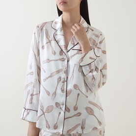 Model wearing Olivia von Halle Lila Sevilla Silverware Pyjama Set in white silk with cutlery print and contrast dark piping trim