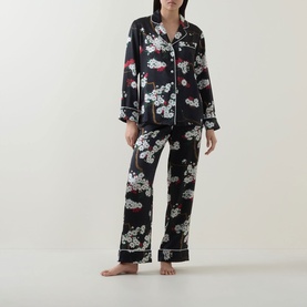 Model wearing Olivia von Halle Lila Ren&eacute; Blossom Pyjama Set in black silk with floral print, long-sleeve shirt and full-length trousers