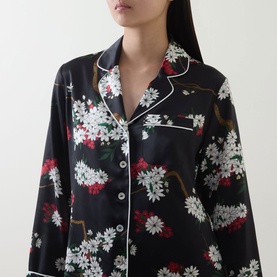Model wearing Olivia von Halle Lila Ren&eacute; Blossom Pyjama Set in Rene, black silk with white and red floral print, white piped collar