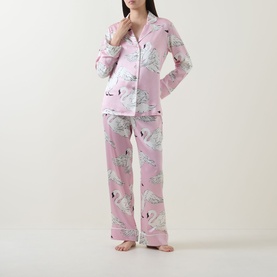 Model wearing Olivia von Halle Lila Selene Swan Pyjama Set in pink silk with all-over swan print, long sleeve shirt and full-length trousers