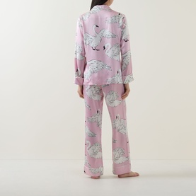 Model wearing Olivia von Halle Lila Selene Swan Pyjama Set in pink silk with all-over swan print, shown from behind, long sleeve top and full-length