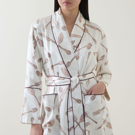 Model wearing Olivia von Halle Capability Sevilla Silverware Robe in cream silk with silverware print, shawl collar, contrast piping and self-tie belt