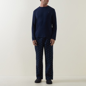Model wearing Tommy Hilfiger Blue Spell Pyjamas Set; navy long-sleeve top with logo and Carbon Navy Flag AOP print trousers
