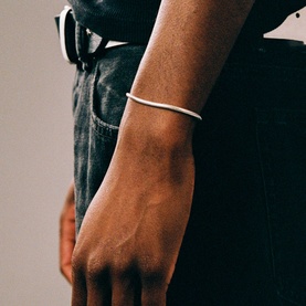 Model with Two Jeys silver slim cuff bracelet worn on wrist, styled with dark jeans and white tee