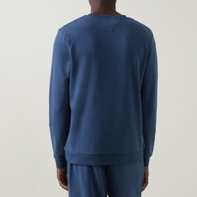 Model wearing blue crew neck sweatshirt, rear view, styled with matching blue joggers