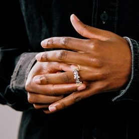 Model with Two Jeys silver ring featuring crystal embellishments, worn on middle finger, styled with a silver chain bracelet.