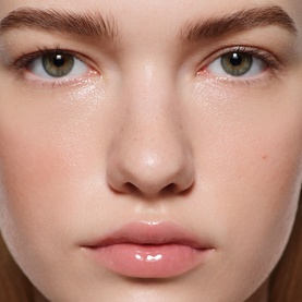 Model wearing Victoria Beckham Posh Gloss in Bikini, a sheer nude-pink lip gloss, paired with a fresh, dewy complexion finish.