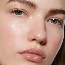 Model wearing Victoria Beckham Posh Gloss in Bikini, a sheer nude-pink lip gloss, paired with a natural, glowing complexion look.
