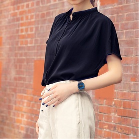 Model with Casio watch in silver and blue, styled with a black short-sleeve blouse and white trousers