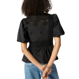 Model wearing Whistles black top with broderie anglaise yoke, puff sleeves and smocked waist, styled with light blue jeans.