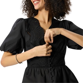 Model wearing Whistles black dress with puff sleeves and crochet lace bodice detail, V-neckline visible at close range