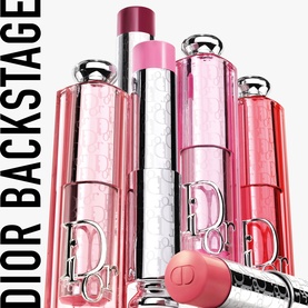Dior Addict Lip Glow collection in assorted pink and berry shades, multiple lip balm sticks displayed upright with translucent caps