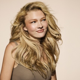 Model with voluminous, tousled blonde hair styled to showcase Fenty Hair Dry Shampoo results, against a neutral background.